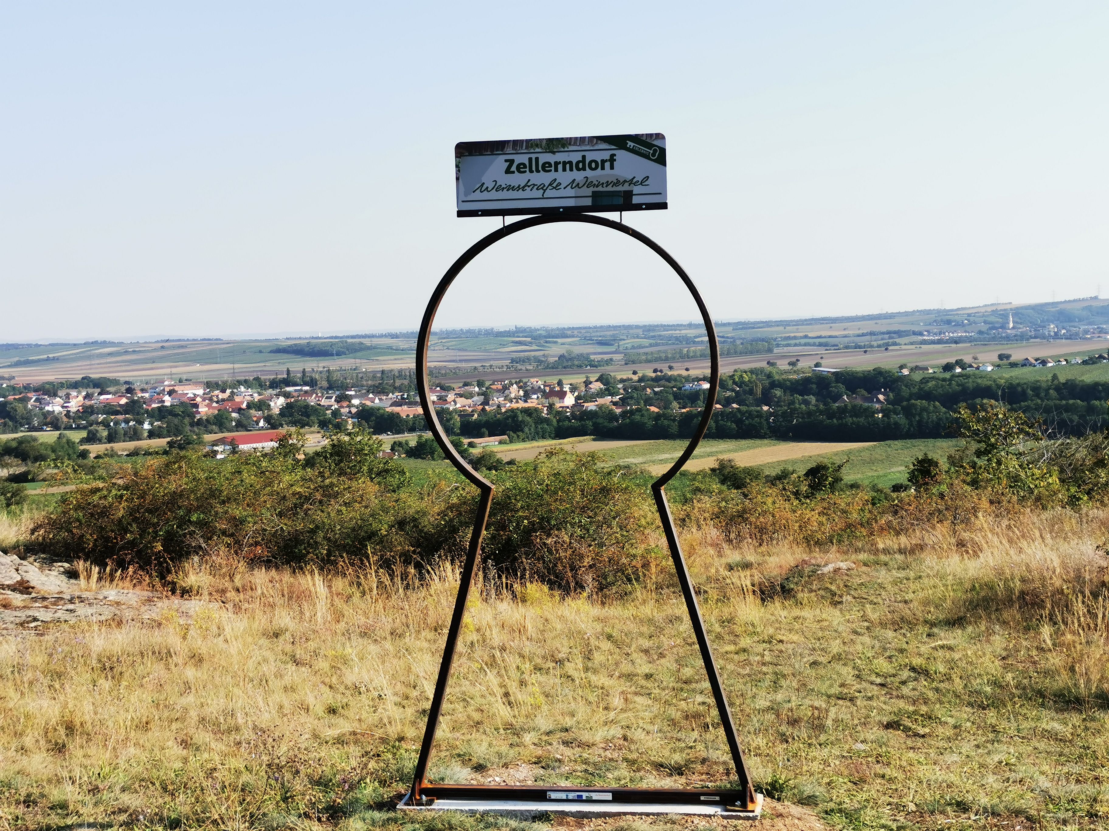 Blick auf Zellerndorf durch eine schlüsselförmige Metallskulptur.