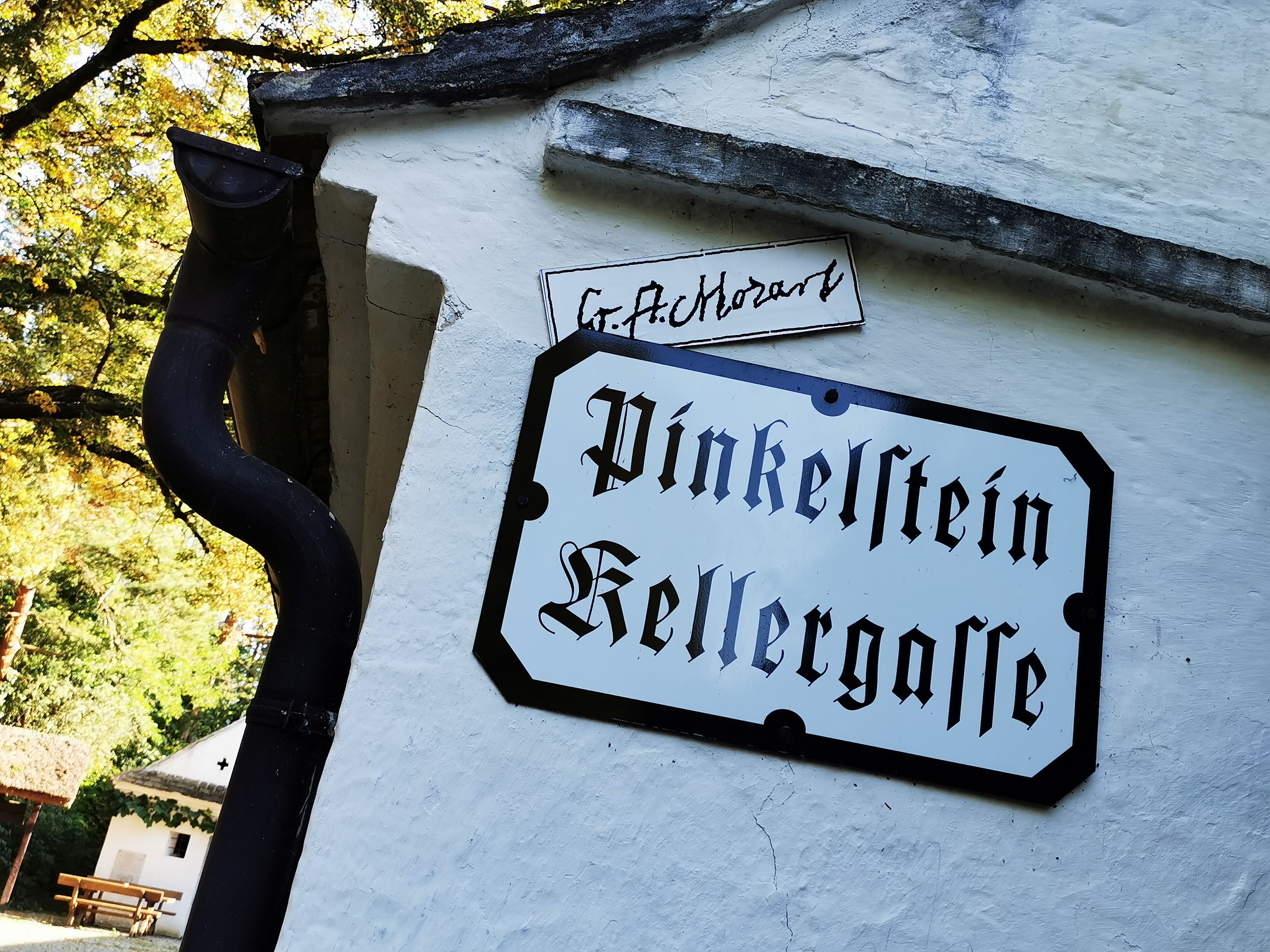Schild mit der Aufschrift 'Pinkelstein Kellergasse' an einer weißen Wand.