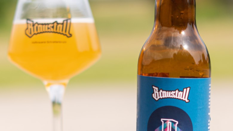 Eine Flasche Braustall Pale Ale und ein Glas mit Bier auf einem Tisch im Freien.