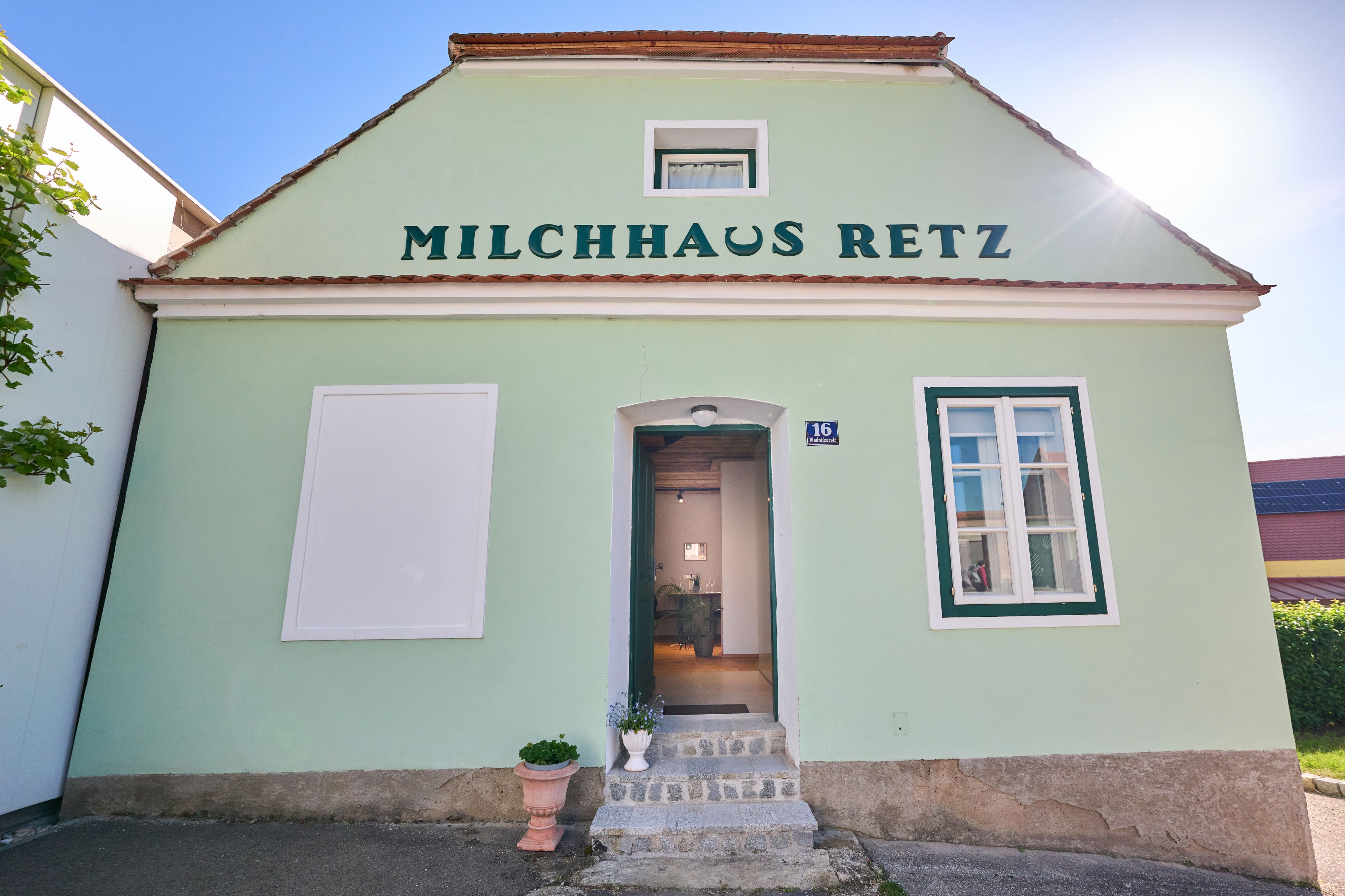 Grünes Gebäude mit der Aufschrift 'Milchhaus Retz' und einer offenen Tür.