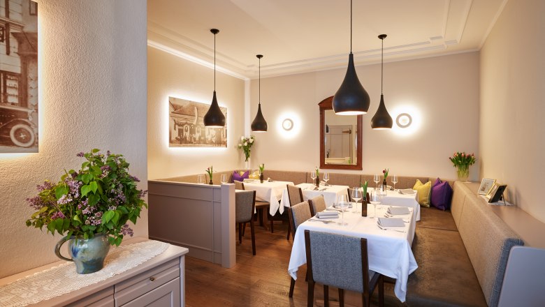 Elegantes Restaurant mit gedeckten Tischen, modernen Lampen und Blumenarrangement.