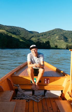 Eine entspannte Bootstour auf der Donau bietet atemberaubende Ausblicke auf die sanften Hügel und Weinberge der Wachau. Der klare Himmel und das sanfte Plätschern des Wassers schaffen eine friedliche Atmosphäre, die zum Verweilen einlädt.