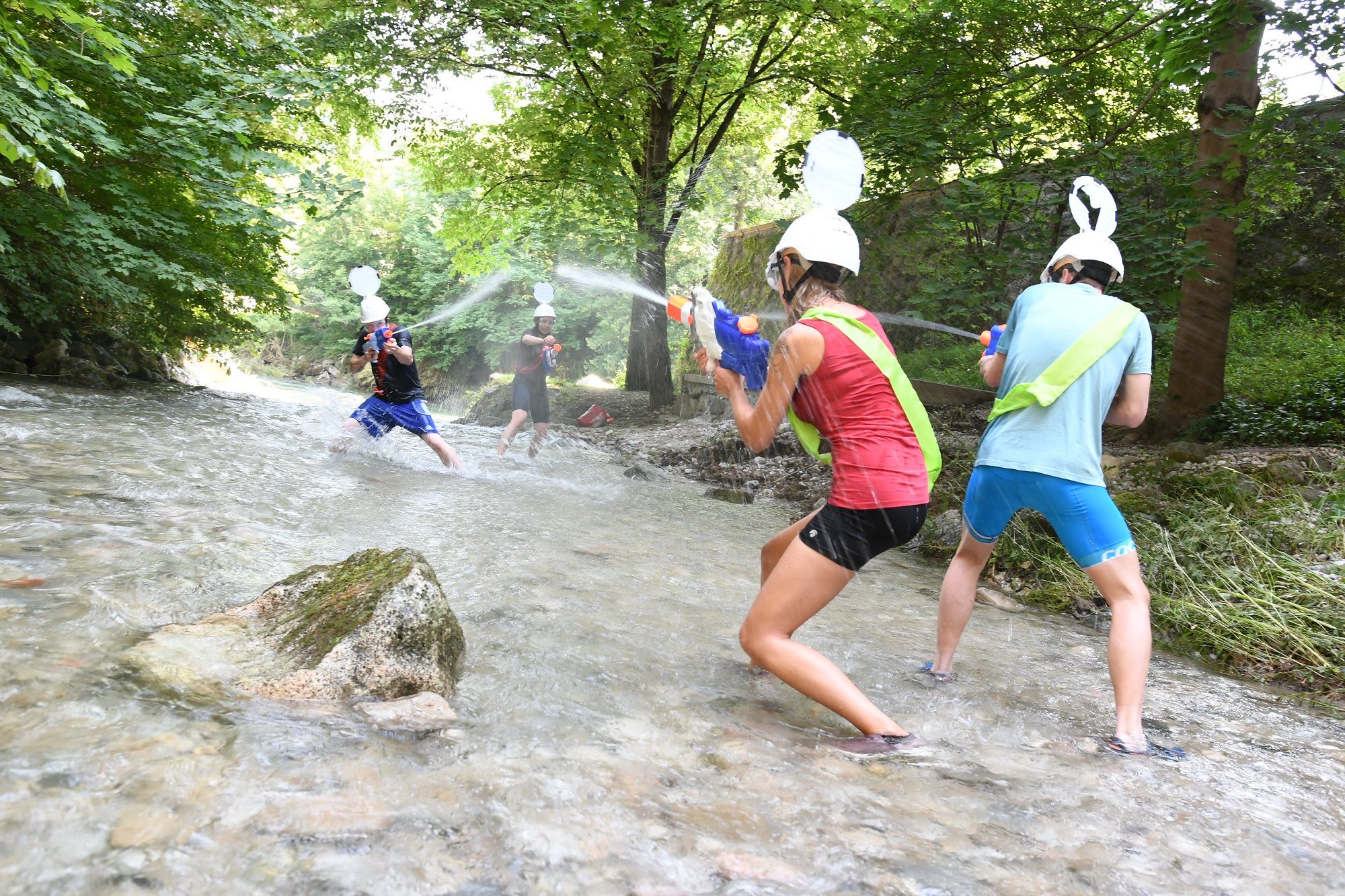 Vier Personen bei einer Wasserschlacht mit Spritzpistolen im Fluss Ybbs