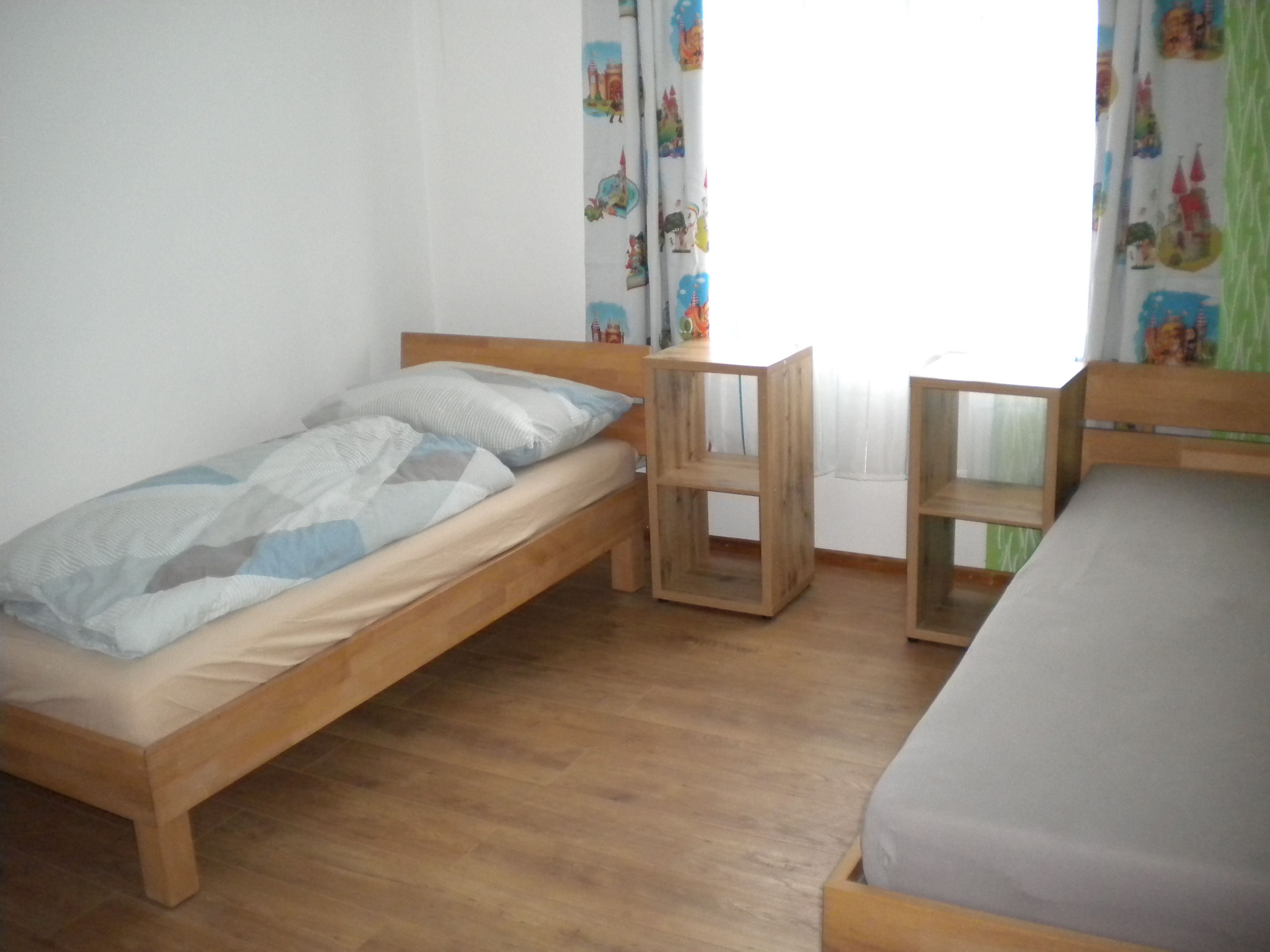 Schlafzimmer mit zwei getrennten Betten und Fenster dahinter