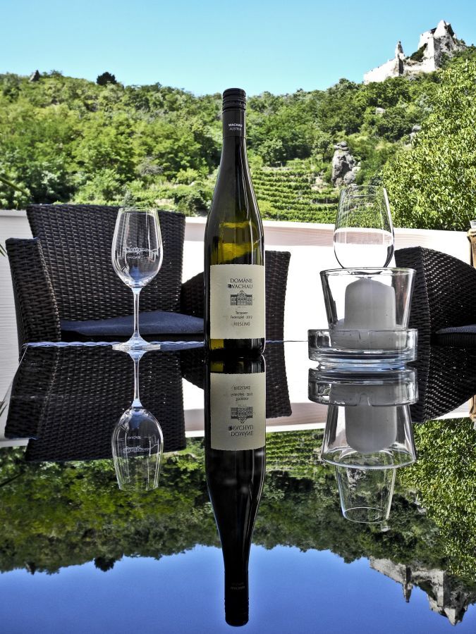 Weinflasche und Gläser auf einem Tisch mit Blick auf Weinberge.