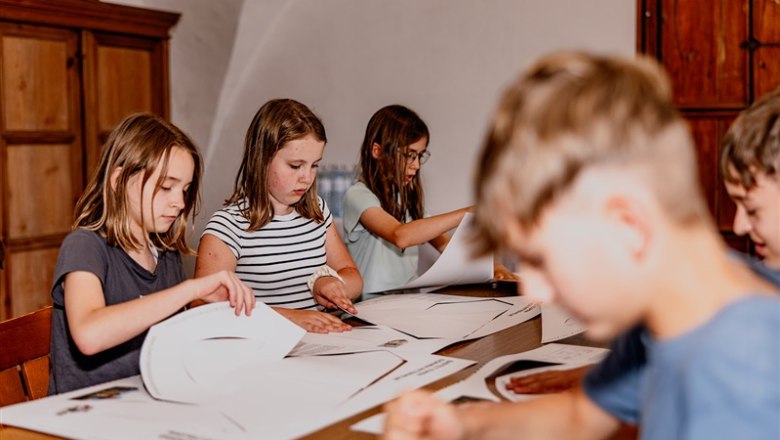 Kinder basteln an einem Tisch mit Papier.