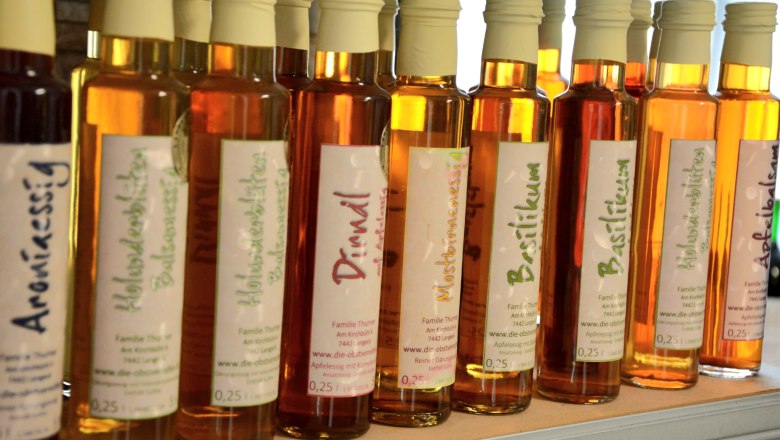 Verschiedene Essigflaschen in einer Reihe auf einem Regal.