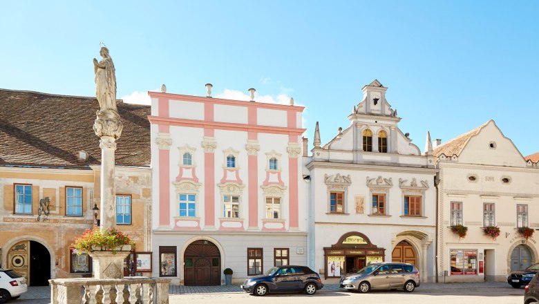 Historische Geb&auml;ude am Hauptplatz von Eggenburg mit einer Statue im Vordergrund.
