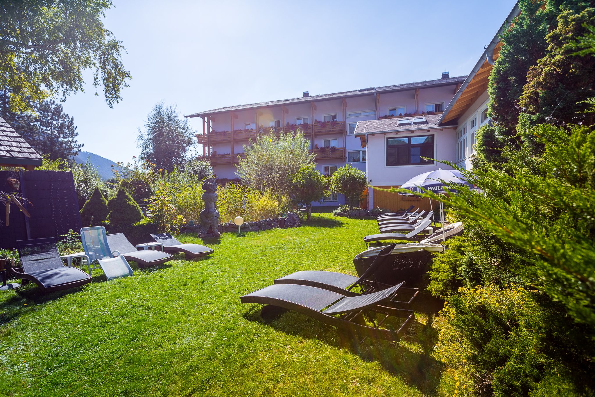 Garten mit Liegen vor dem rosa Haus