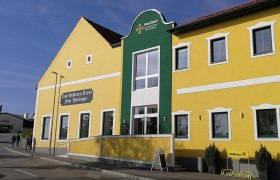 Gelbes Gebäude mit grüner Fassade und der Aufschrift 'Zum Goldenen Kreuz Fam. Haslinger'.