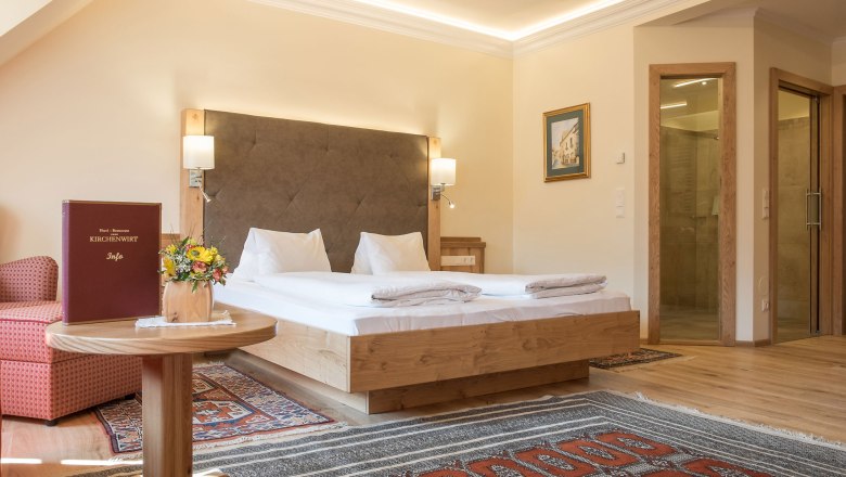 Hotelzimmer mit Doppelbett, Teppichen und Holzmöbeln.