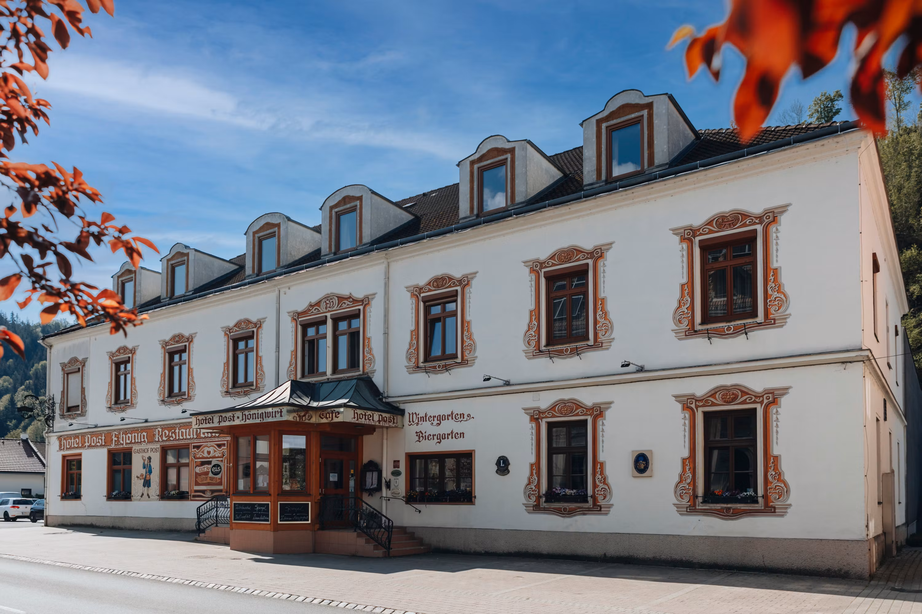 Historisches Gebäude mit dekorativen Fensterrahmen und Schildern für Hotel und Restaurant.
