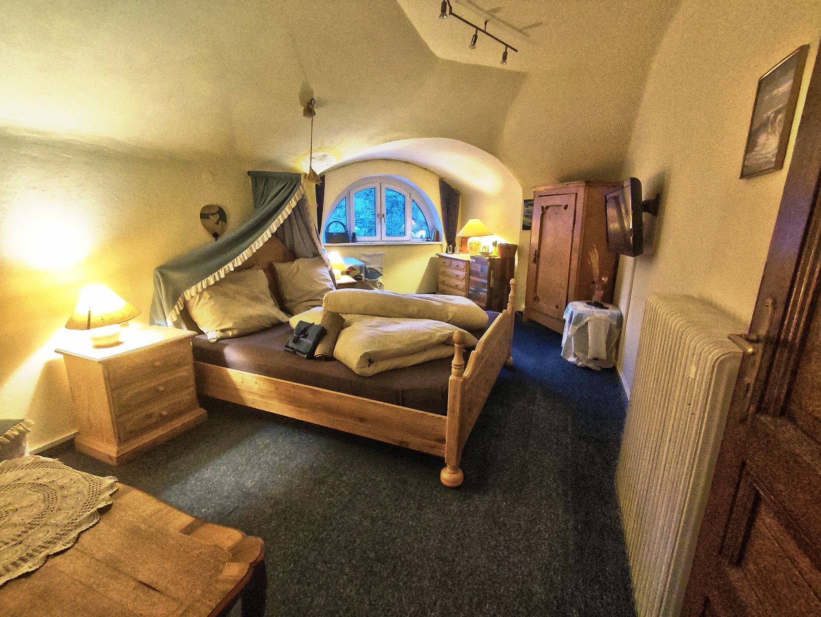 Gemütliches Schlafzimmer mit Holzmöbeln und gewölbter Decke.