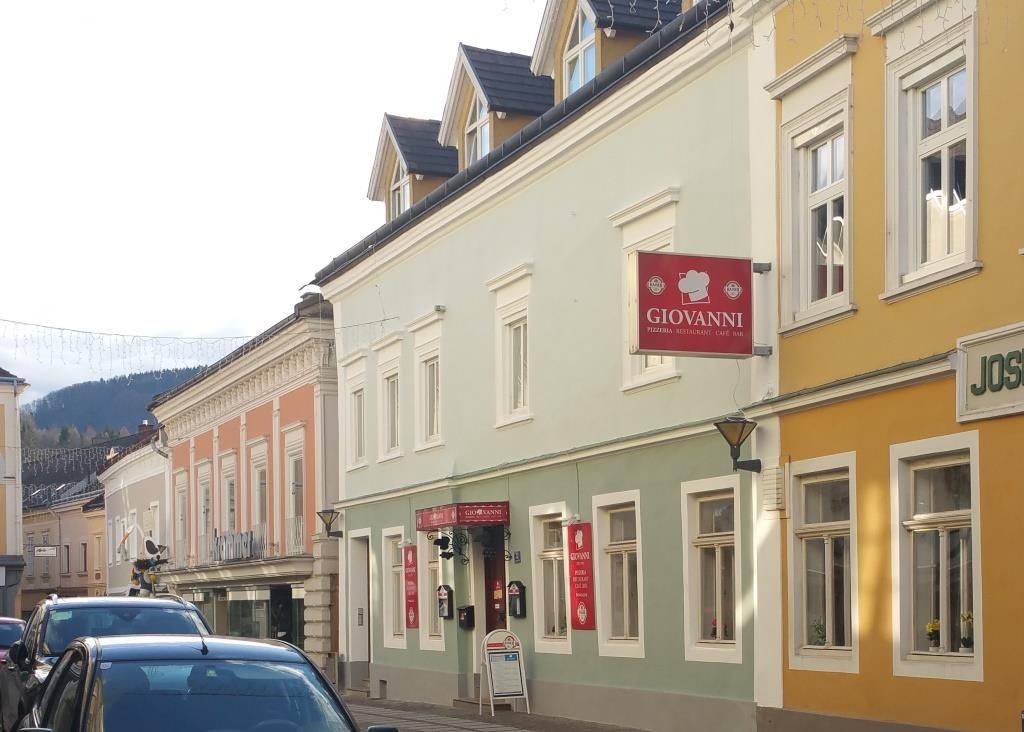 Straßenszene mit bunten Gebäuden und einem Schild mit der Aufschrift 'Giovanni'.