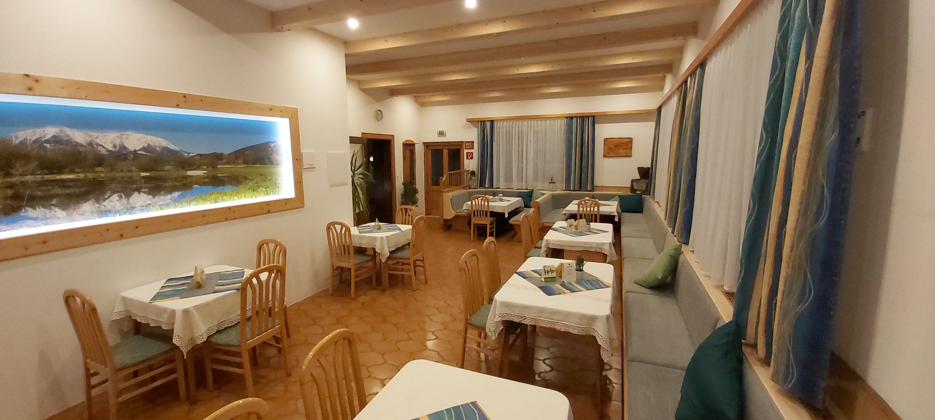 Gemütliches Restaurant mit Holzmöbeln und Bergbild an der Wand.