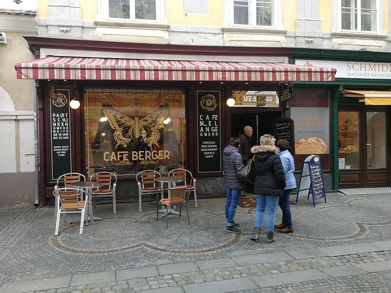 Außenansicht des Cafe Berger mit Sitzgelegenheiten und Personen vor dem Eingang.