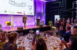 Blick auf den Galaabend zum 20-jährigen Jubiläum des Convention Bureau Niederösterreich im Großen Burgsaal der Burg Perchtoldsdorf: Ein Künstler steht auf der Bühne, während die Gäste an gedeckten Tischen das Programm verfolgen.
