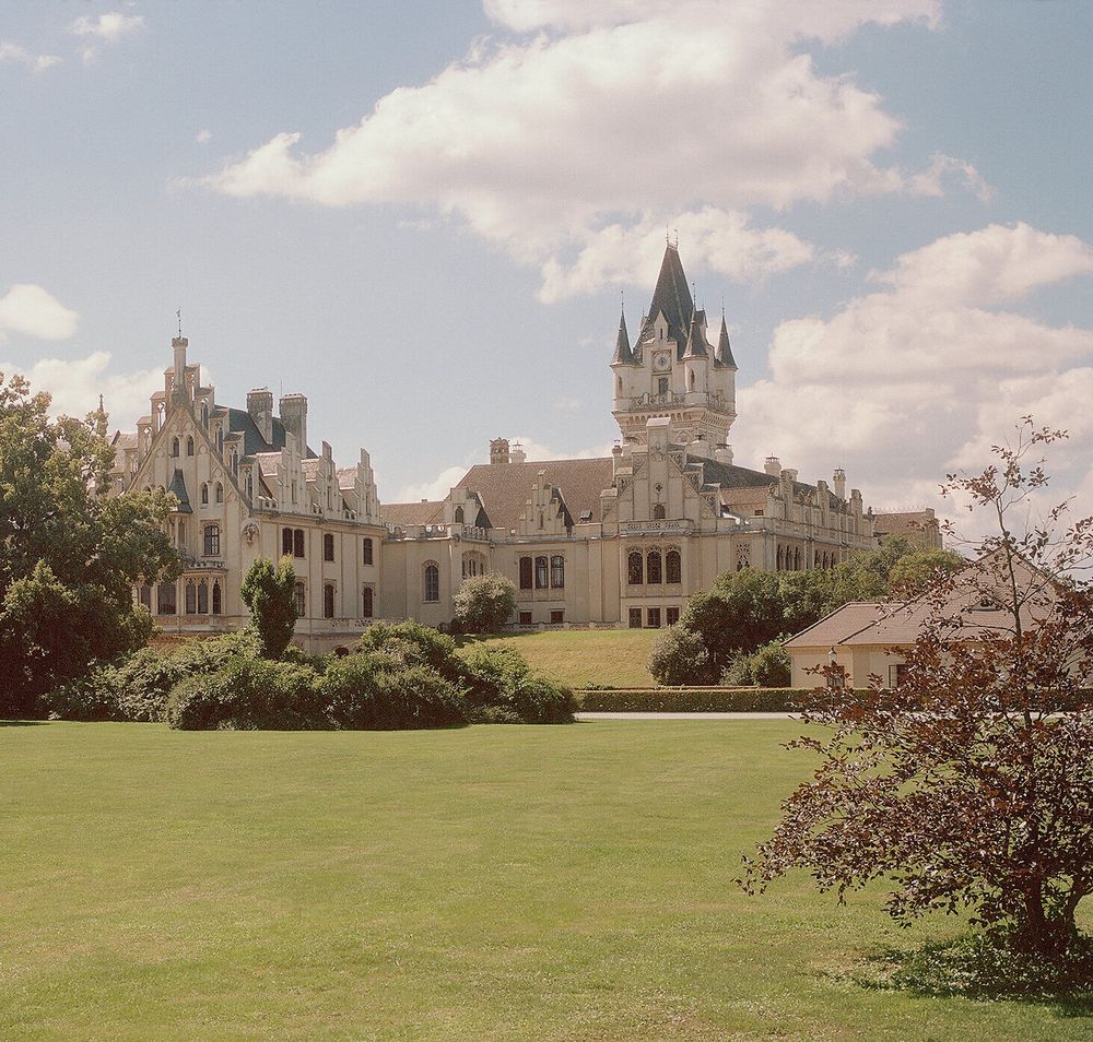 Schloss Grafenegg mit weitläufigem Rasen und Bäumen im Vordergrund.