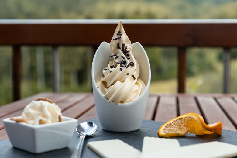 Ein Dessert mit Softeis, Schokostreuseln, Waffeln und Orangenscheibe auf einem Tisch.