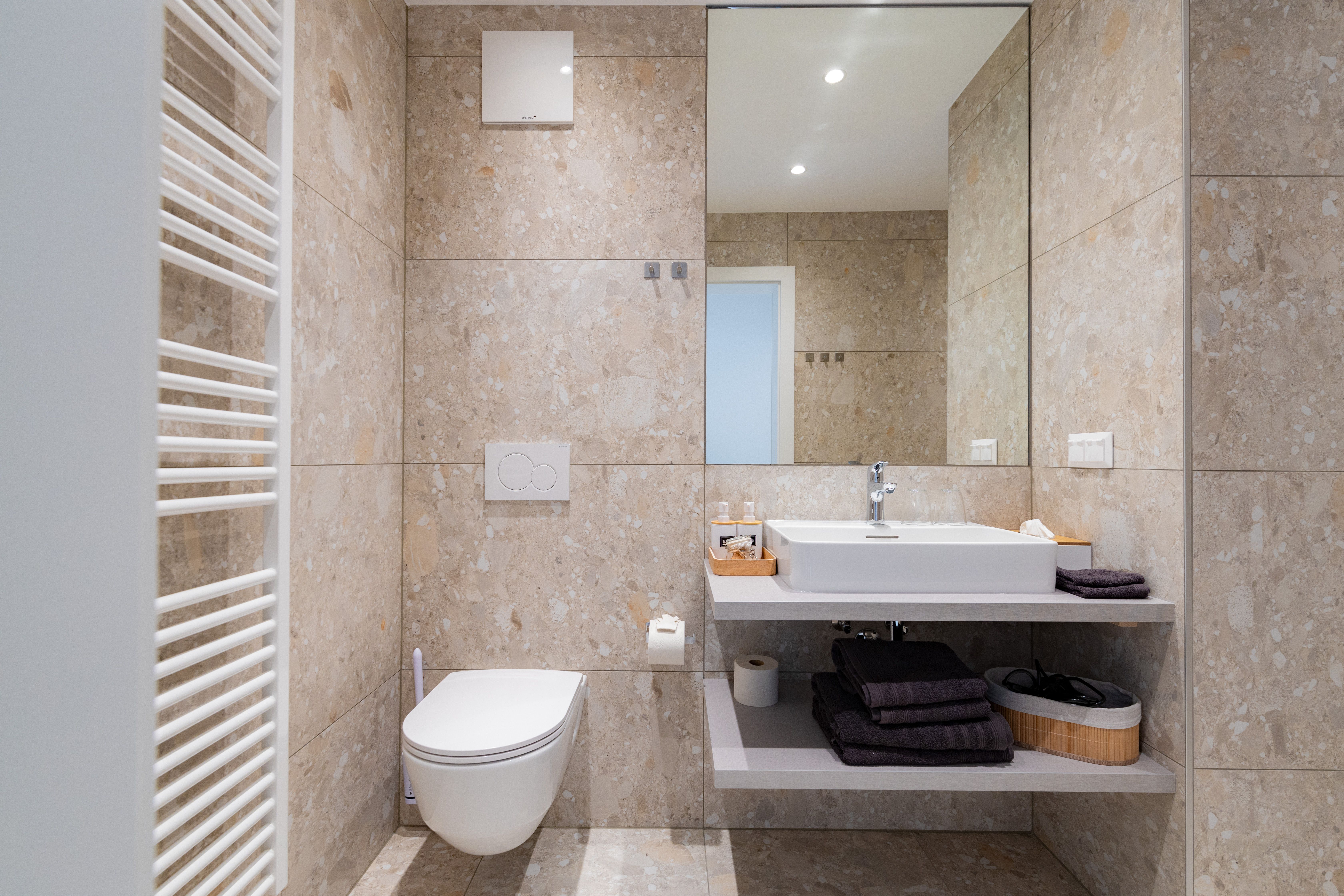Modernes Badezimmer mit Waschbecken, Spiegel, Toilette und Handtuchhalter.