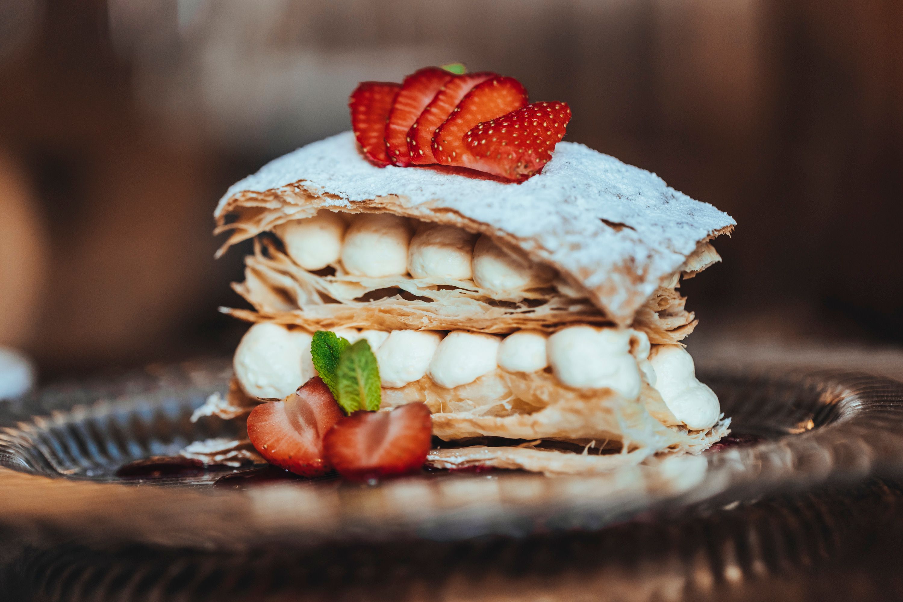 Eine Cremeschnitte mit Blätterteig, Sahne und Erdbeeren auf einem Teller.