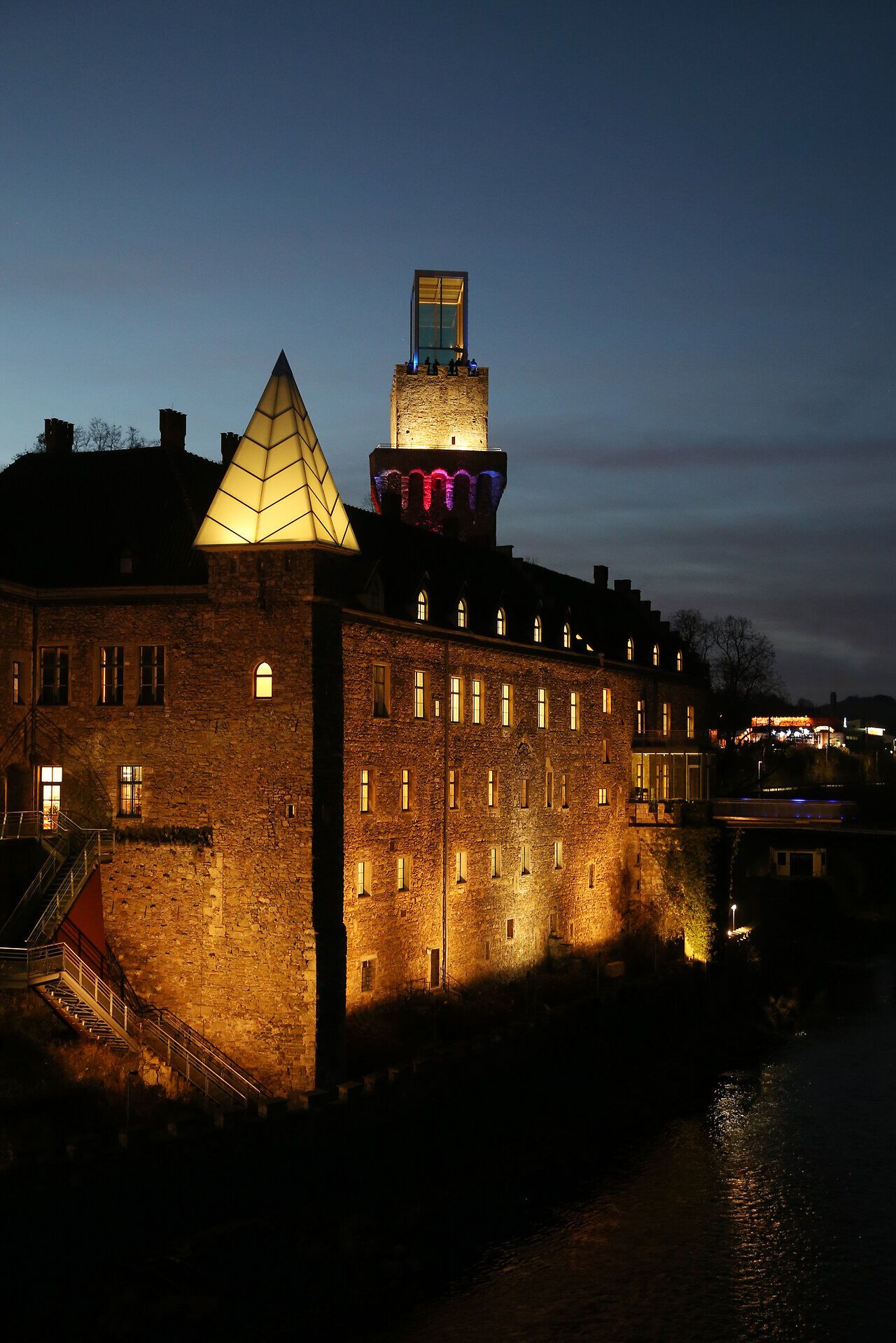 In der sanften Dämmerung erstrahlt das Schloss Rothschild in warmen Lichttönen, während der Fluss leise plätschert. Die harmonische Verbindung von historischer Architektur und modernem Design schafft eine magische Atmosphäre, die zum Verweilen einlädt.