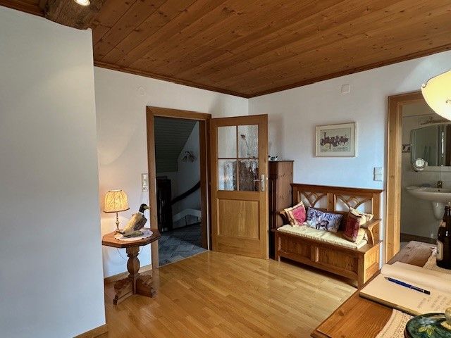 Holzvertäfeltes Zimmer mit Bank, Tischlampe und offenem Zugang zu einem Badezimmer.