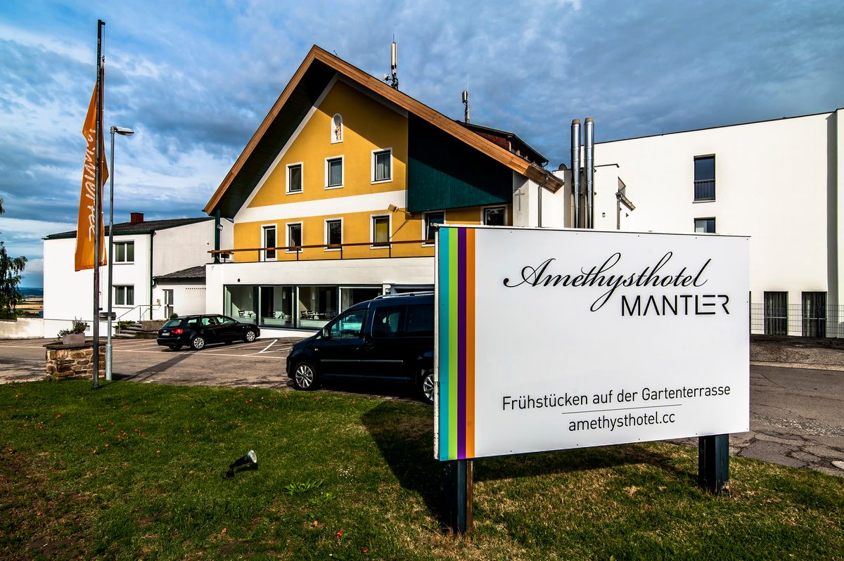 Außenansicht des Amethysthotels Mantler mit Parkplatz und Schild.