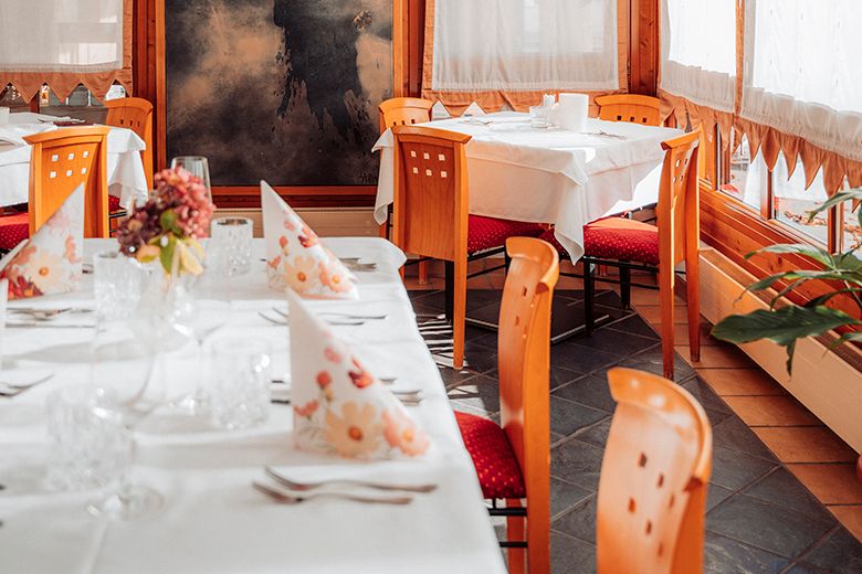 Elegantes Restaurant mit gedeckten Tischen, Holzstühlen und dekorativen Servietten.