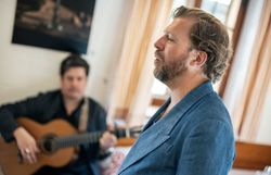 Der Tenor Julian Prégardien singt für die Gäste im Triad. Begleitet wird er von einem Mann mit einer Gitarre.