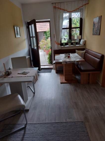 Gemütliches Gästezimmer mit Esstisch, Stühlen und Bank, Blick auf Terrasse.