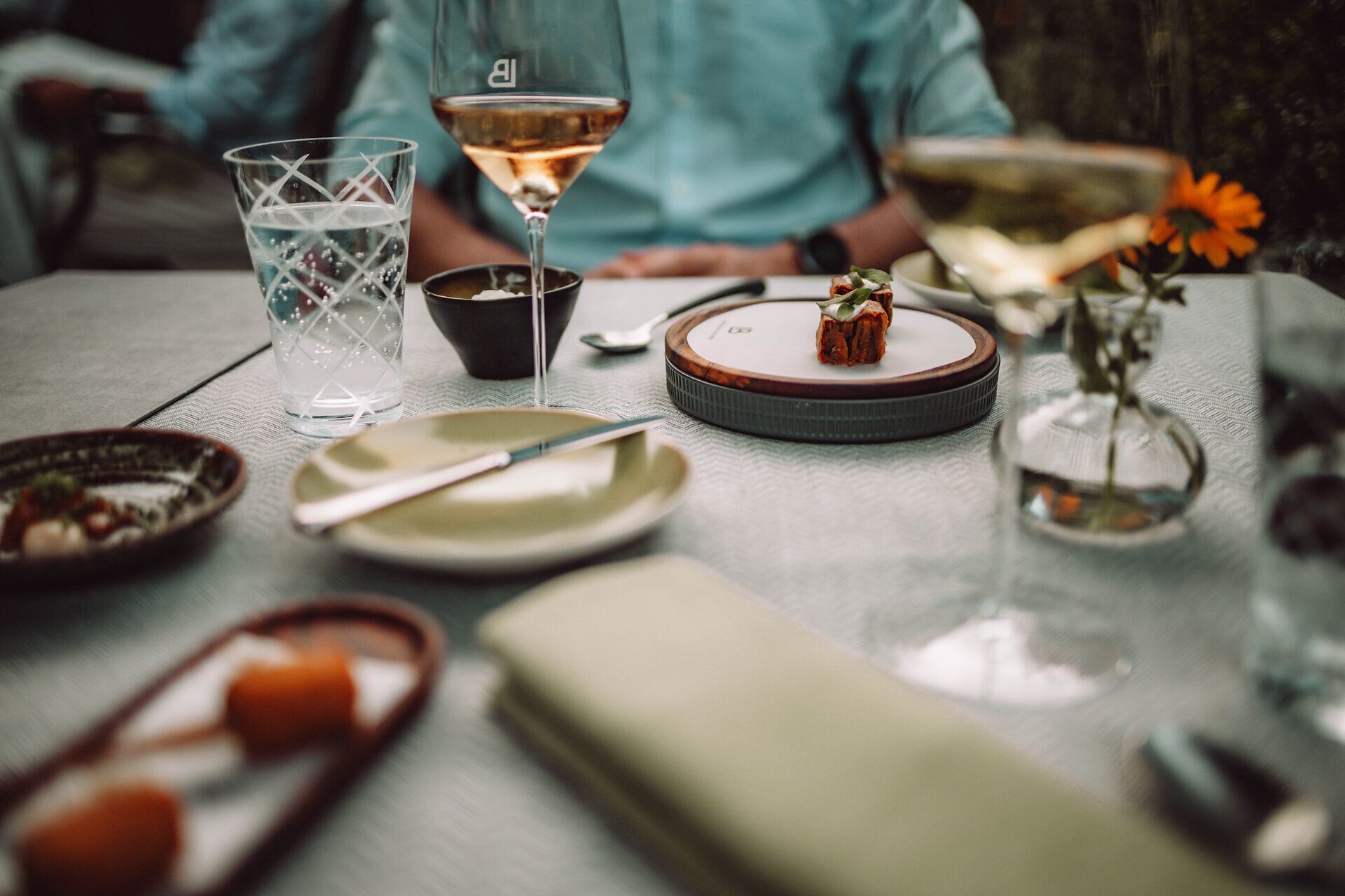 Genießen Sie einen entspannten Abend in einem stilvollen Ambiente, umgeben von köstlichen Speisen und erlesenen Weinen. Die sanften Farben des Sonnenuntergangs spiegeln sich in den Gläsern wider und schaffen eine einladende Atmosphäre für gesellige Stunden.