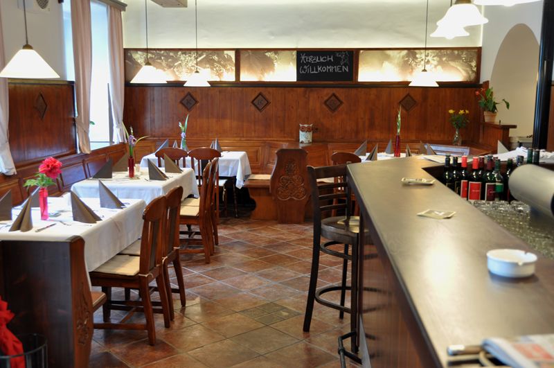 Innenansicht eines gemütlichen Restaurants mit Holzmöbeln und gedeckten Tischen.