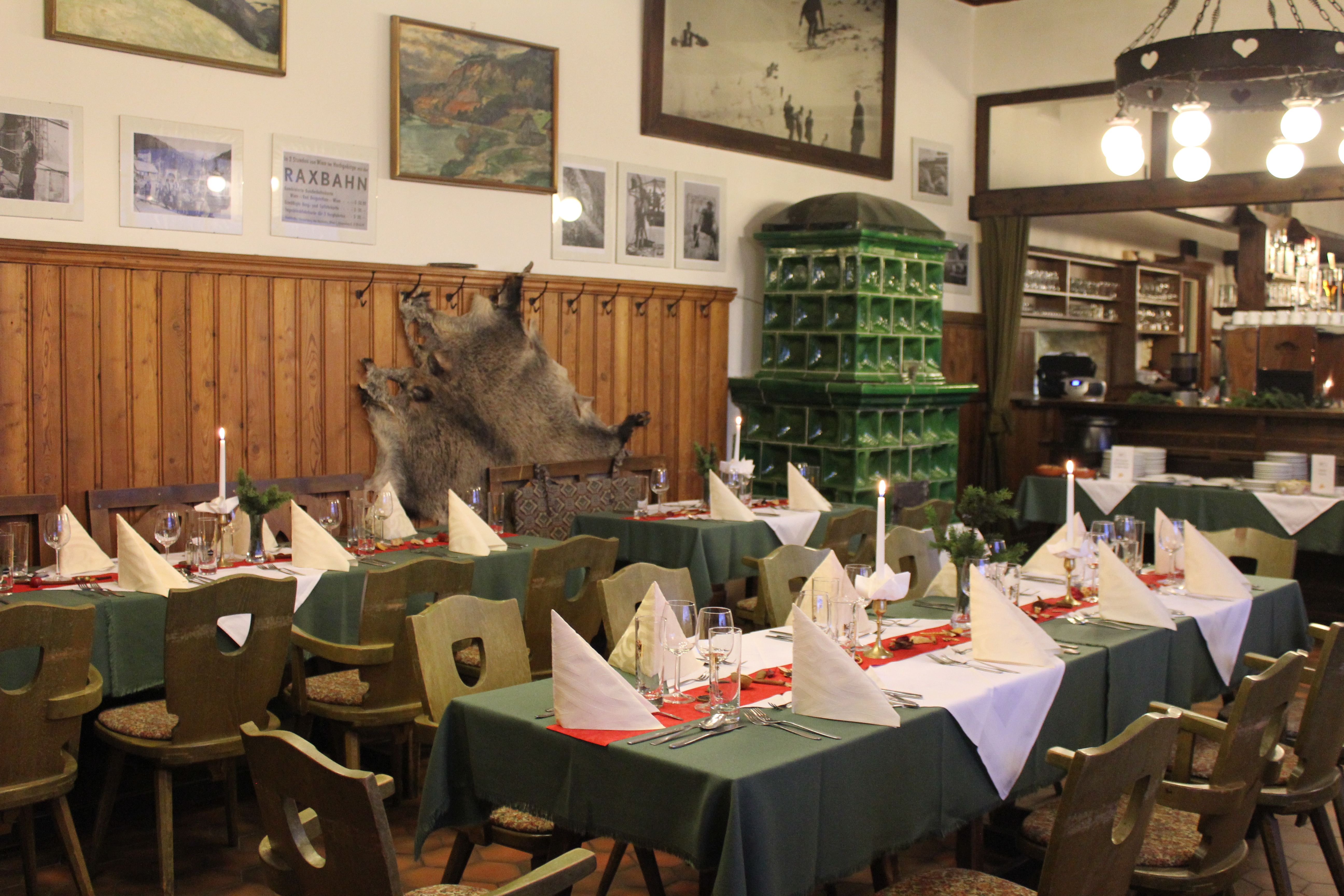 Gemütlicher Gastraum mit gedeckten Tischen, Holzmöbeln und grüner Kachelwand.