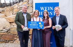Vier Personen stehen vor einem Weinherbst-Niederösterreich-Aufsteller und präsentieren gemeinsam das Weinherbst-Schild sowie die aktuelle Weinherbst-Broschüre.