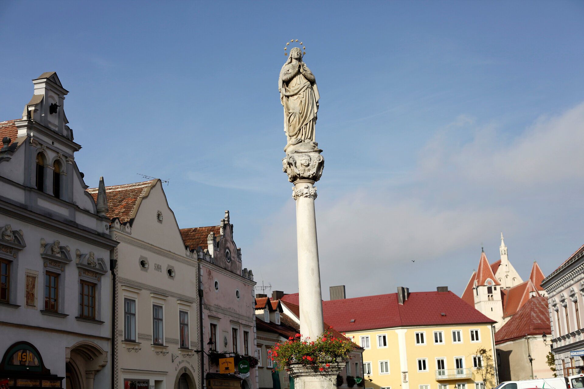 Statue auf einer Säule in Eggenburg mit historischen Gebäuden im Hintergrund.