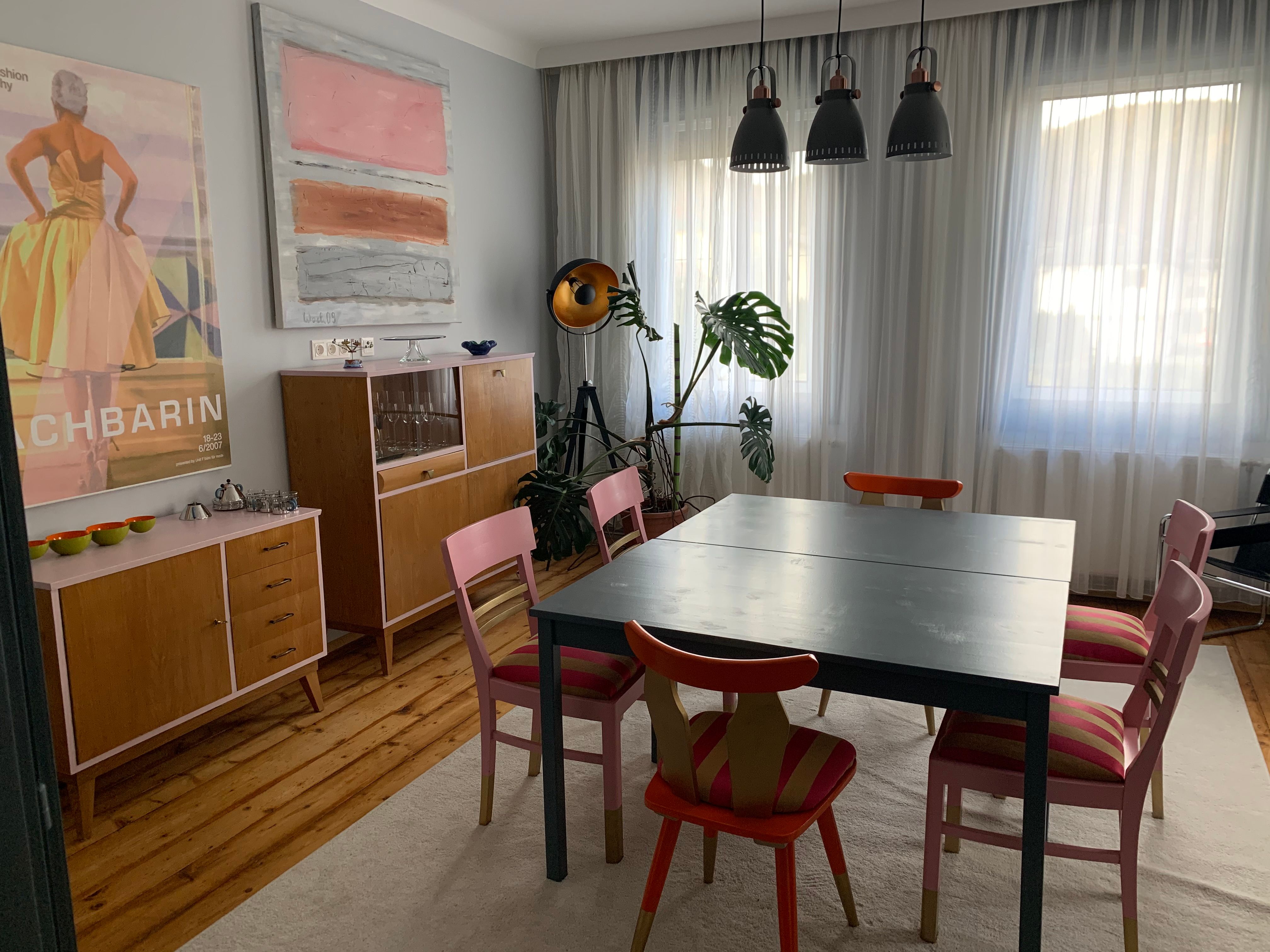 Essbereich mit Tisch, Stühlen, Kommoden und Kunstwerken an der Wand.