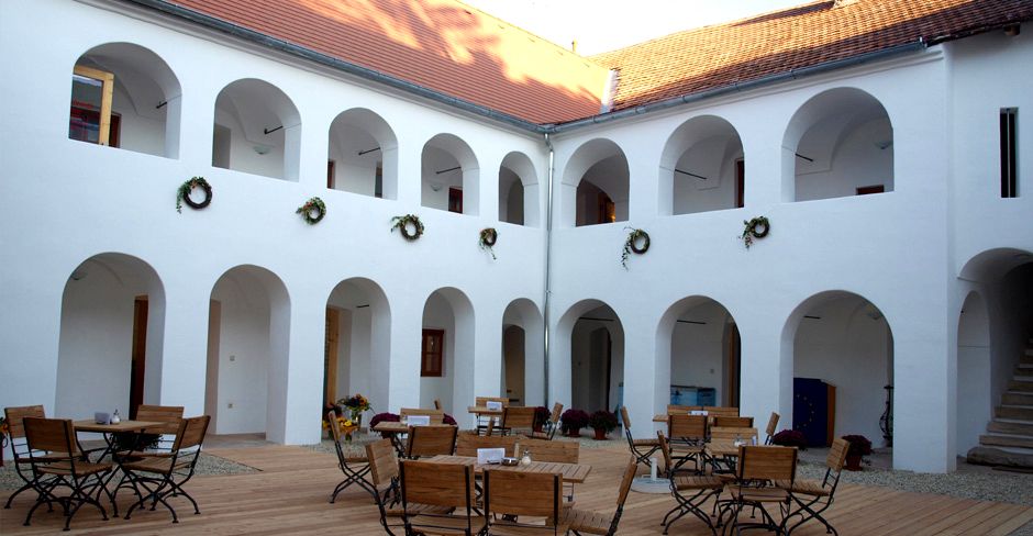 Innenhof des Eisenhuthauses mit Arkaden und Holzmöbeln.