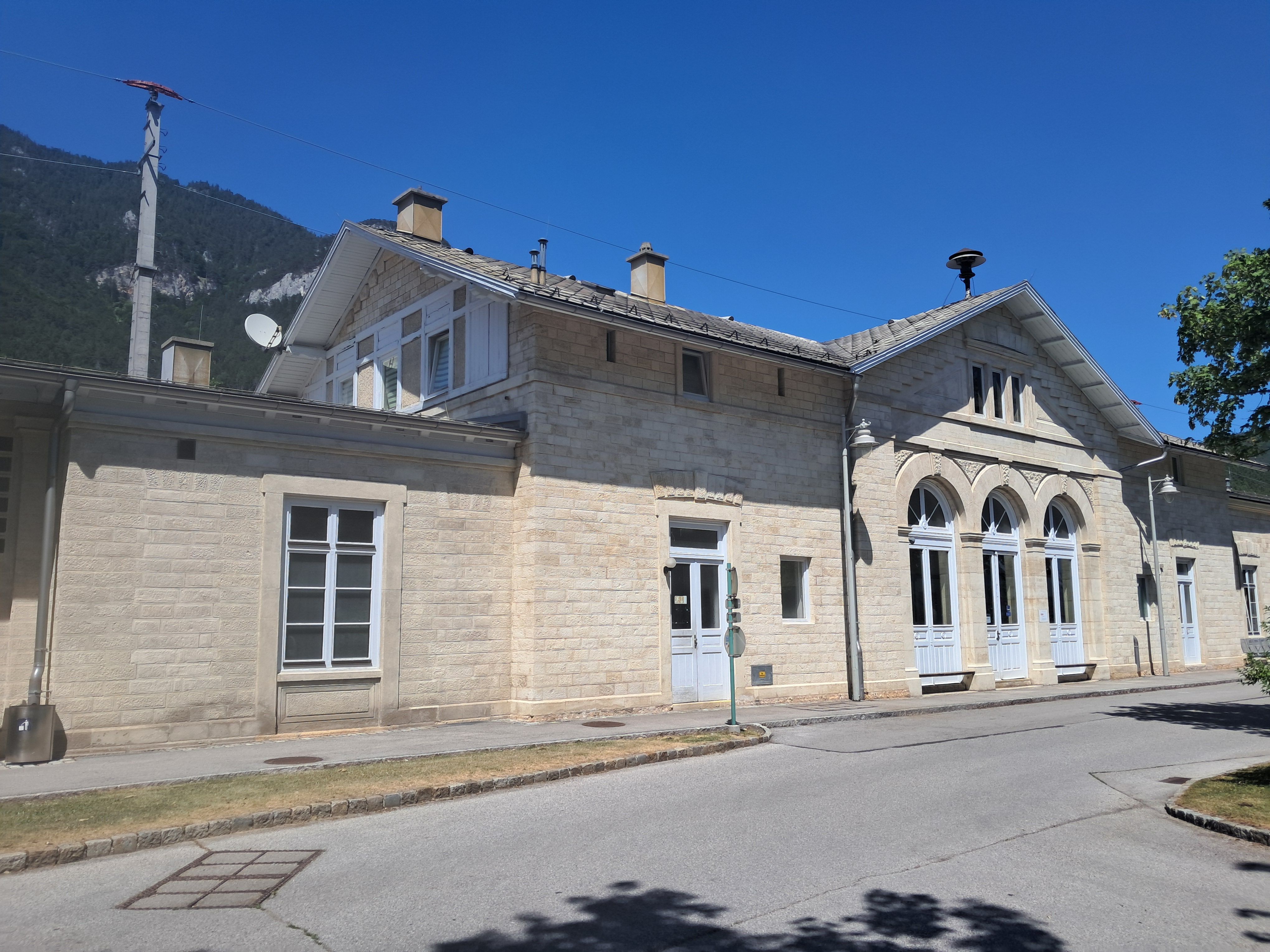 Bahnhof Payerbach-Reichenau mit historischem Gebäude und blauen Himmel.