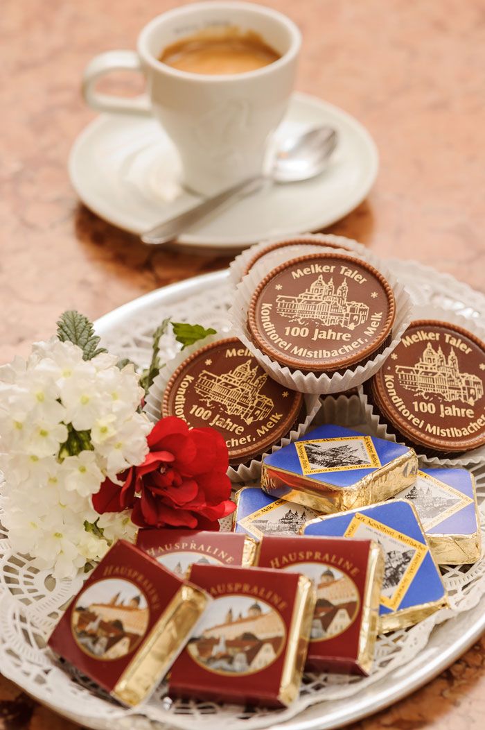 Ein Teller mit Pralinen und Schokolade, daneben eine Tasse Kaffee.