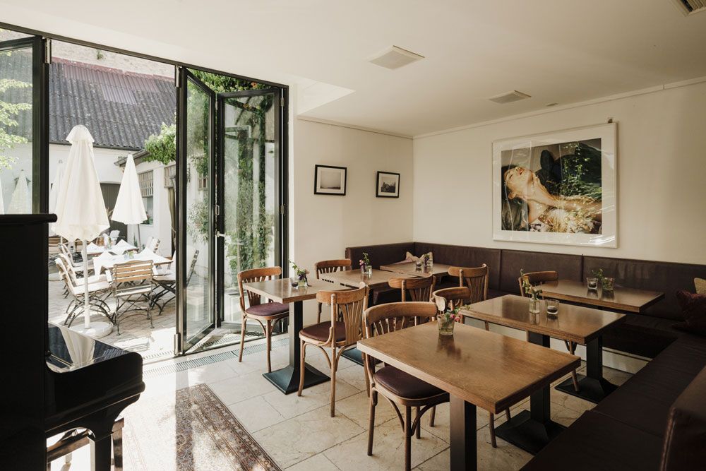 Gemütliches Gastzimmer mit Holztischen, Kunst an der Wand und Terrasse im Freien.