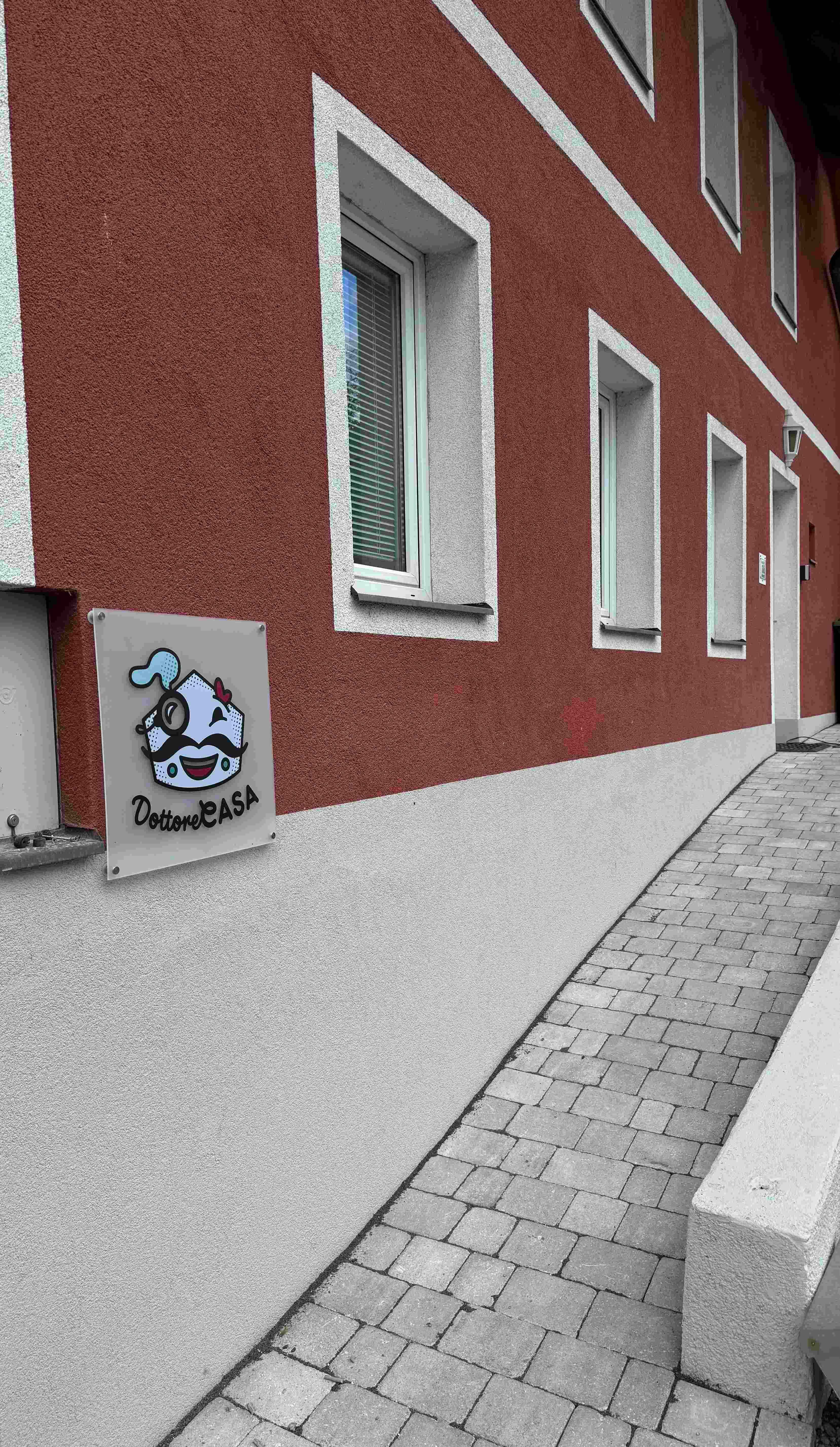 Außenansicht eines Gebäudes mit roter Fassade und einem Schild mit der Aufschrift 'Dottore Casa'.