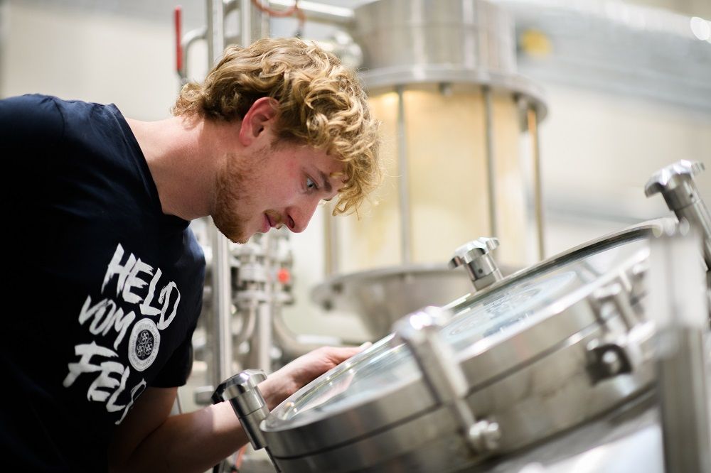 Ein Mann schaut in einen Braukessel in einer Brauerei.