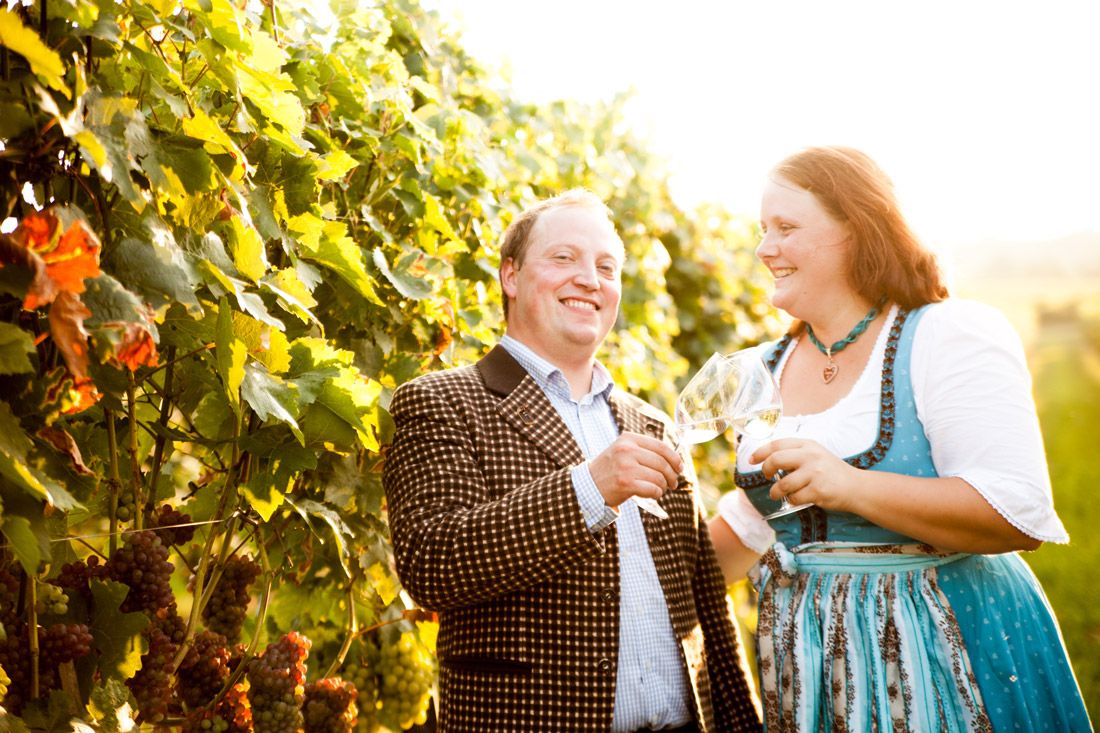 Ein Mann und eine Frau stoßen mit Weingläsern in einem Weinberg an.