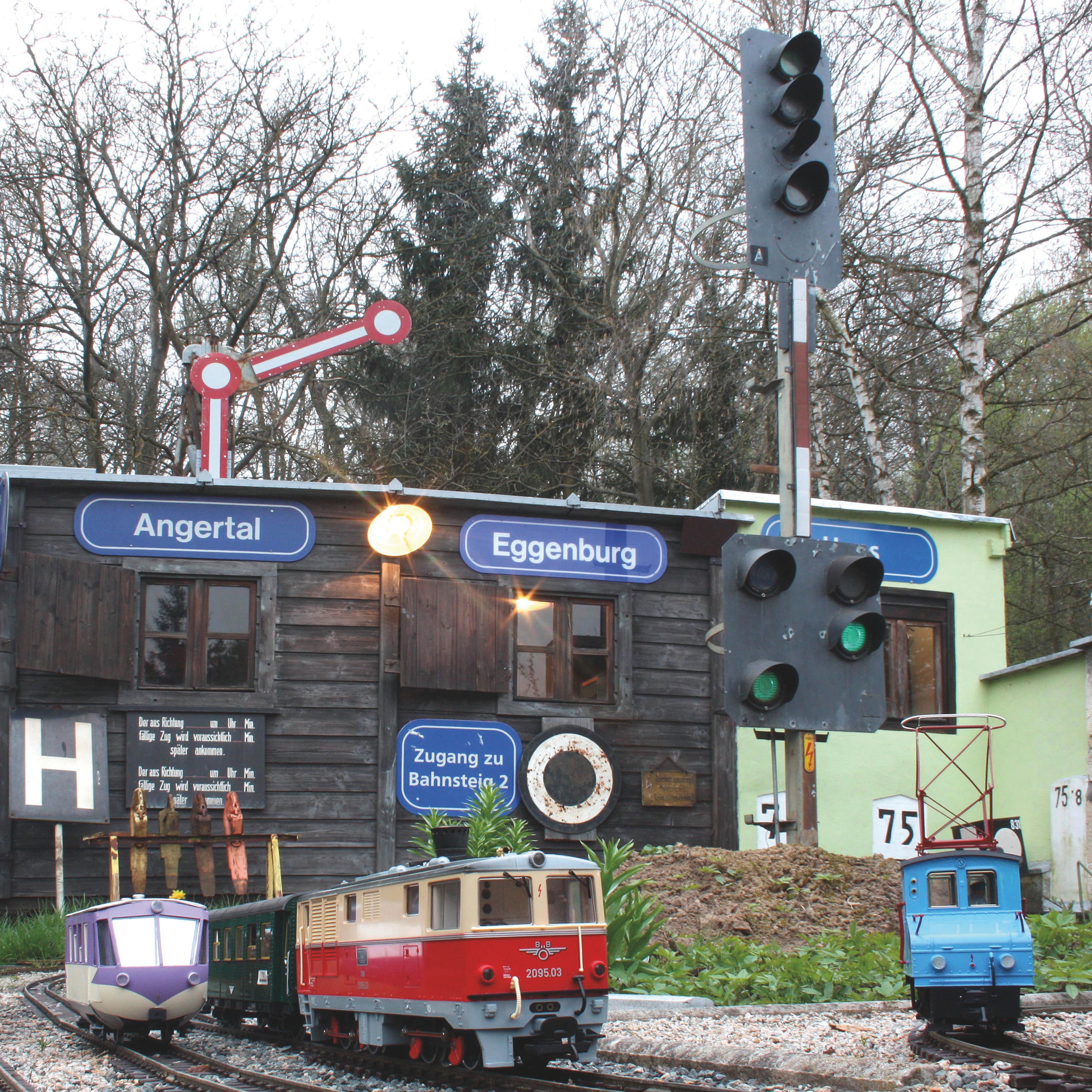 Modelleisenbahn mit Zügen vor einem kleinen Gebäude mit Schildern 'Angertal' und 'Eggenburg'.