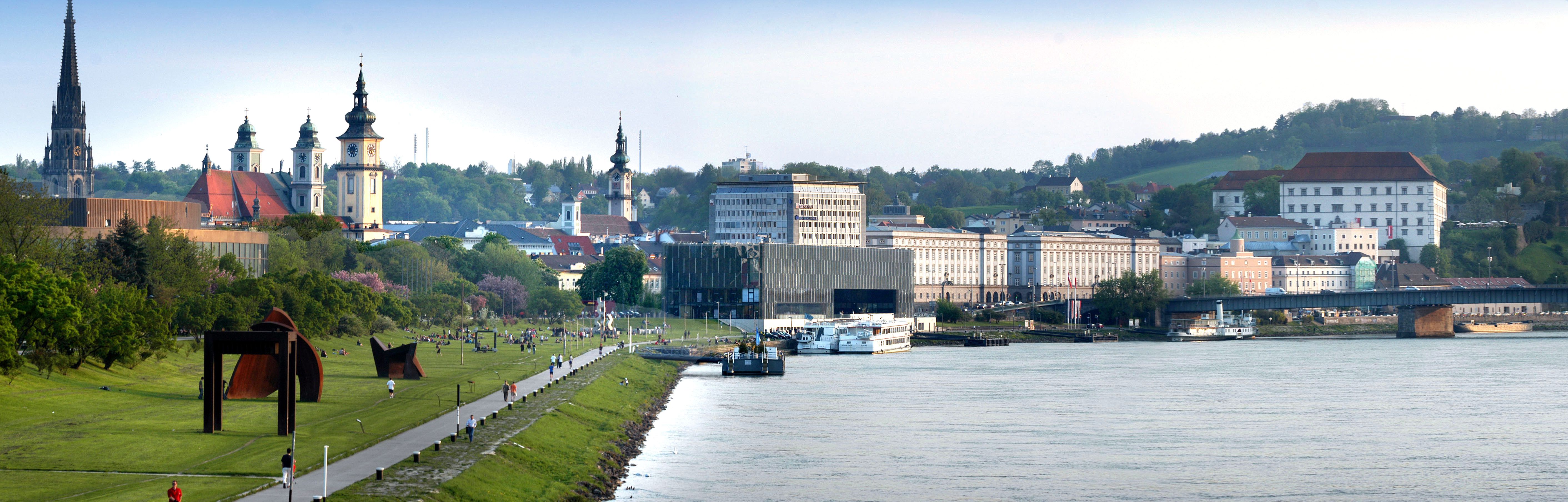 Panorama von Linz mit Donau, Kirchen und moderner Architektur.