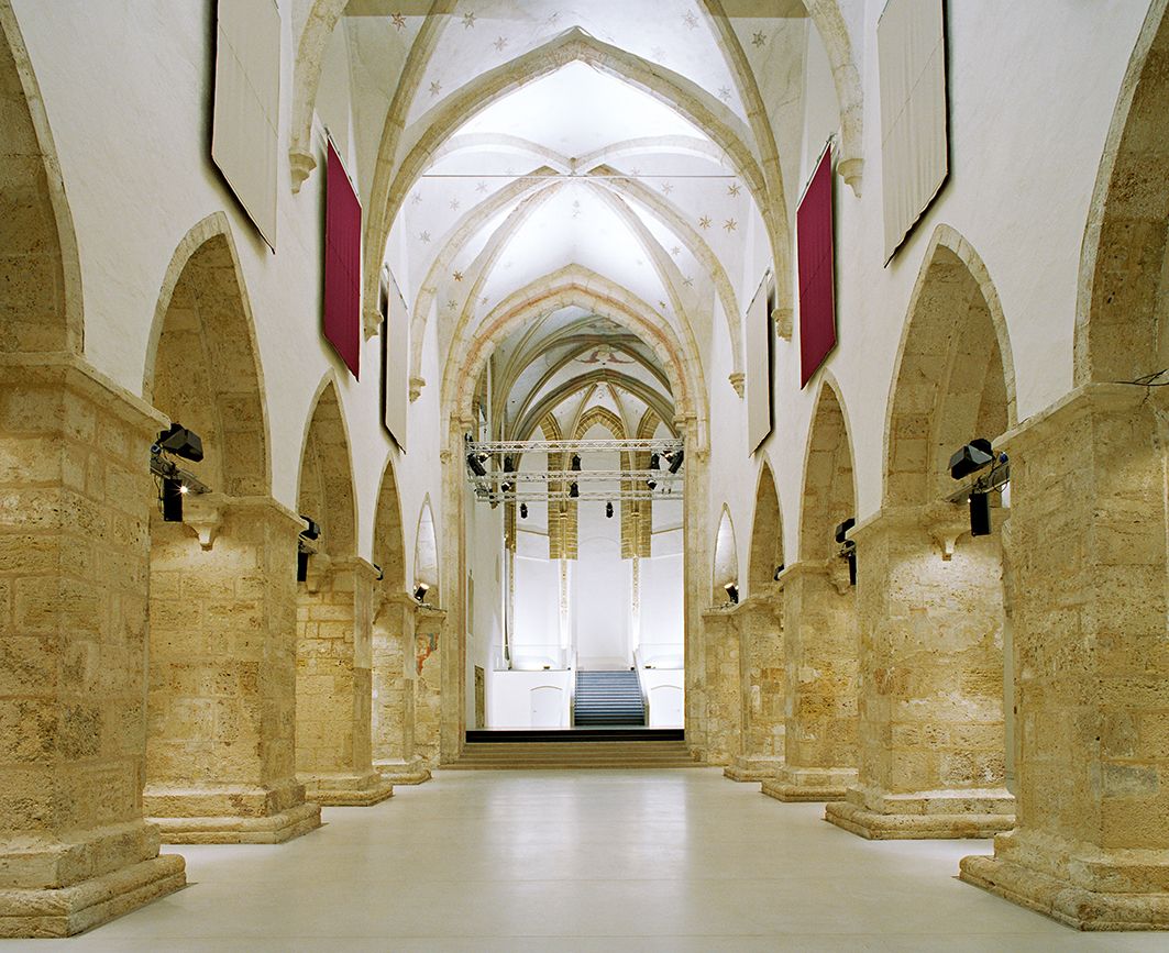 Innenansicht der Minoritenkirche in Krems mit gotischen Bögen und moderner Beleuchtung.