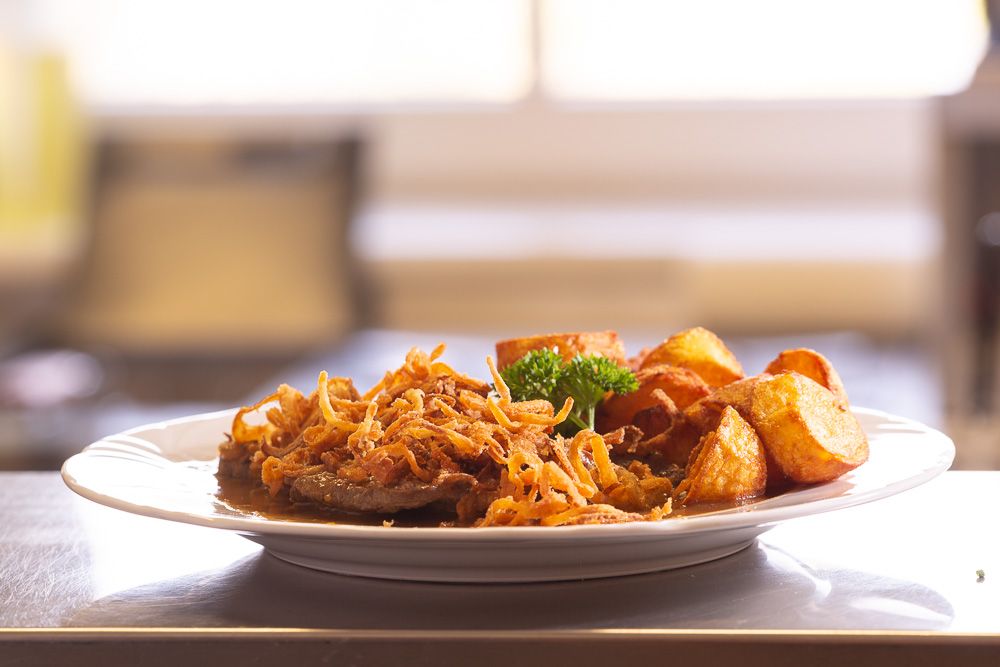 Ein Teller mit Zwiebelrostbraten, Röstzwiebeln und Bratkartoffeln.