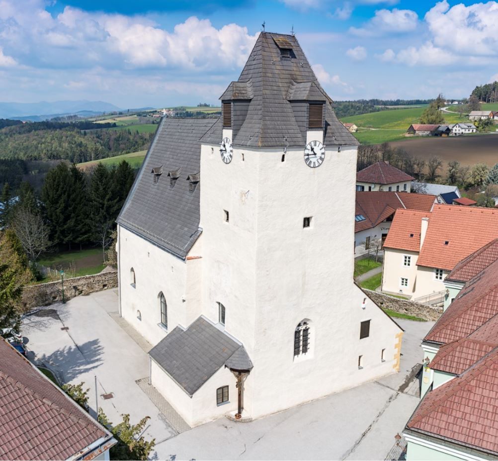 Wehrkirche Lichtenegg mit massiven Uhrturm und umliegenden Gebäuden.