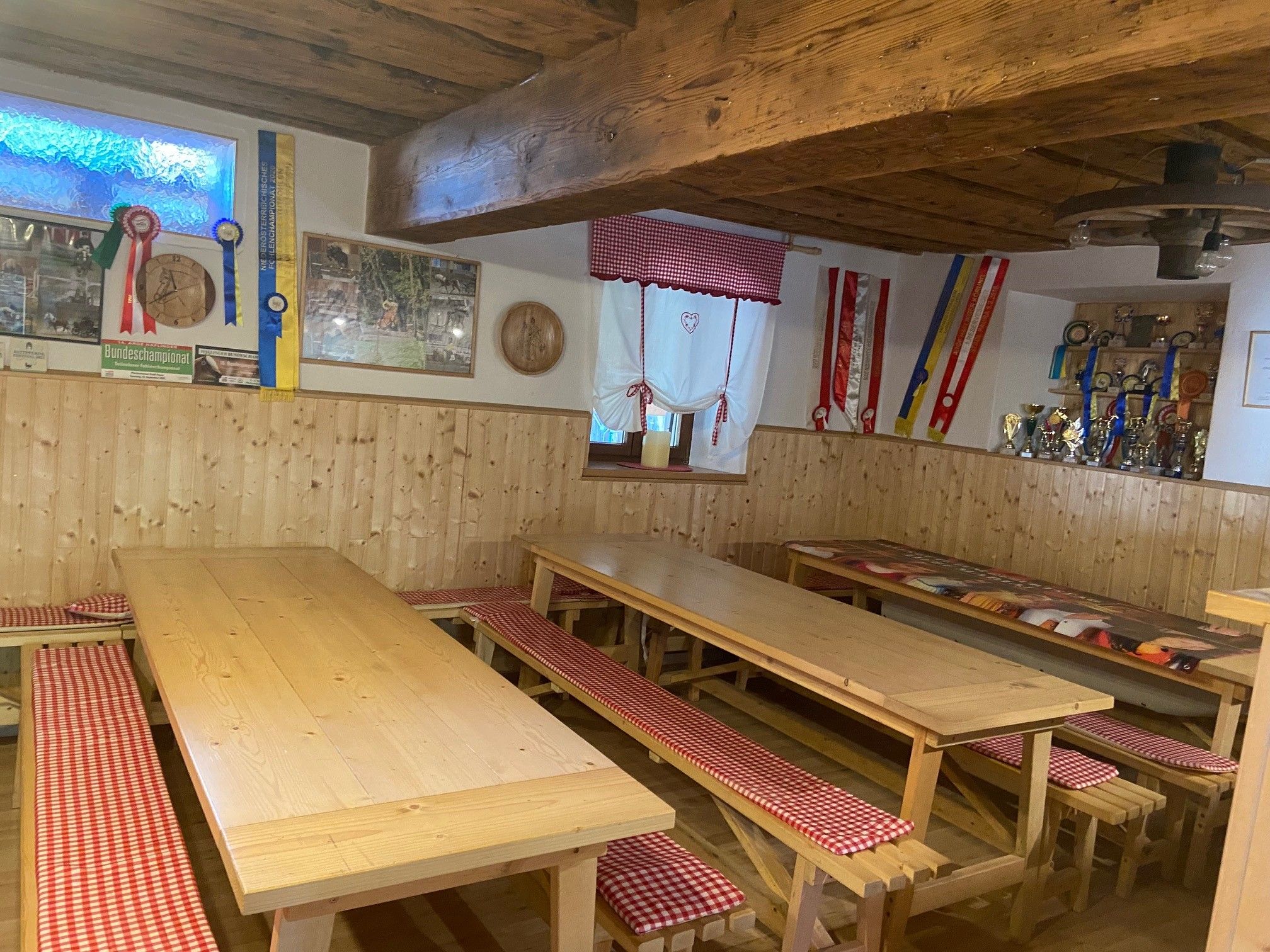 Gemütlicher Gemeinschaftsraum mit Holztischen, Bänken und Dekorationen an den Wänden.